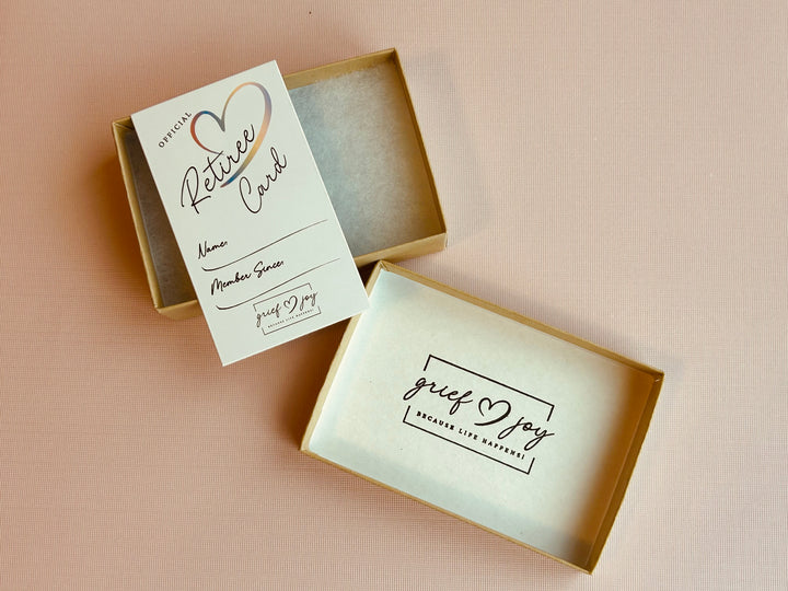 Grief & Joy Official Retiree Card laying on top of gift box