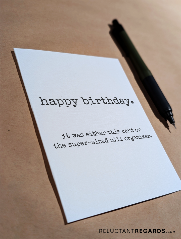 funny birthday card or pill organizer greeting card on table